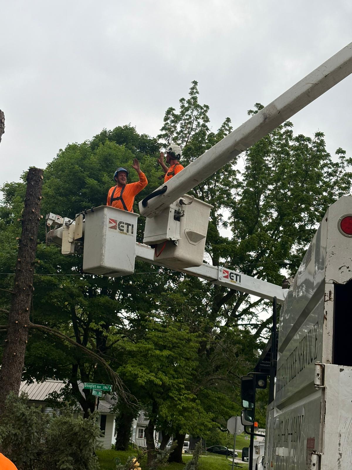 Two crew high-five from bucket-truck lift