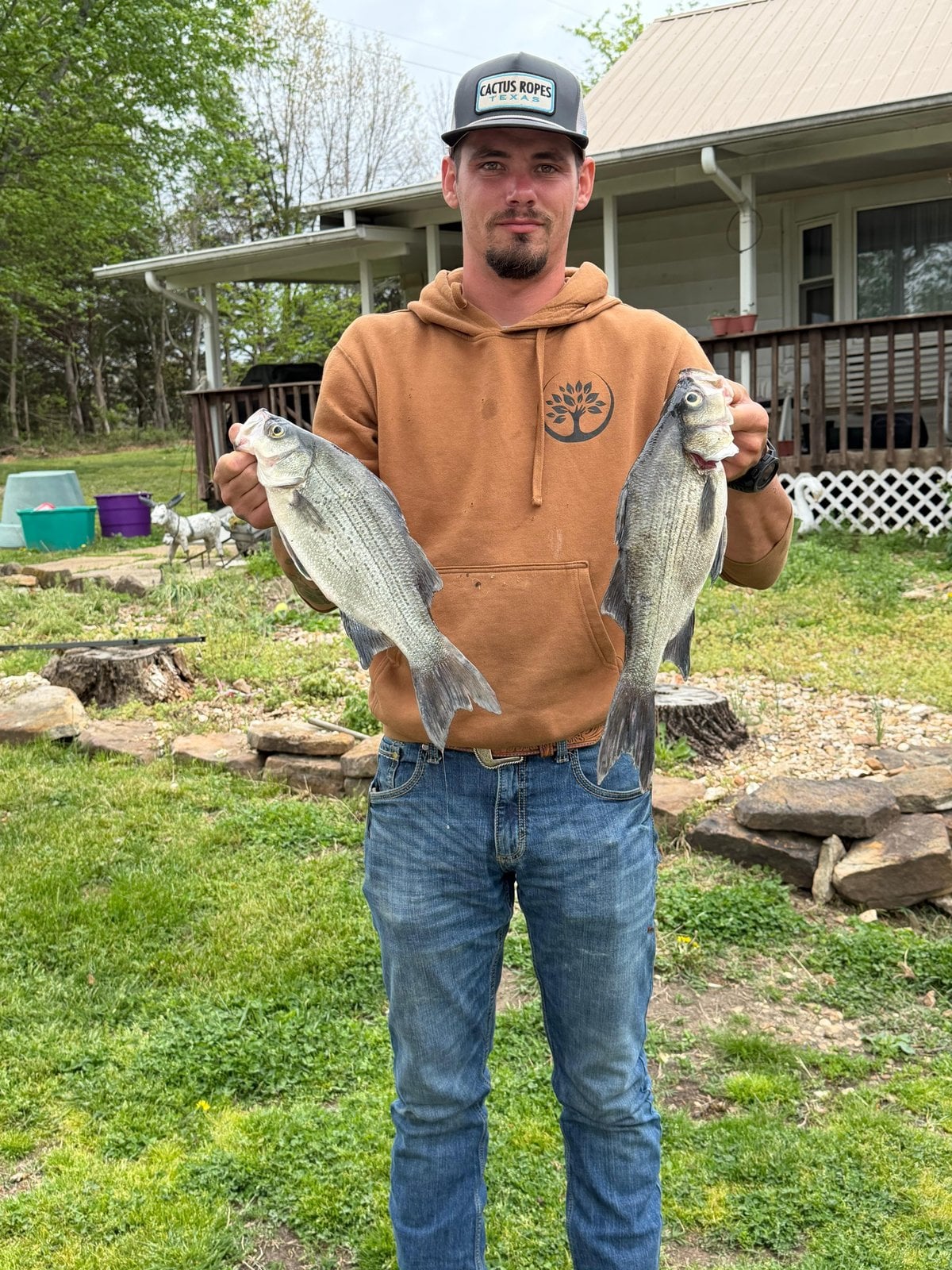 CJ Horsey in a Trufast hoodie, holding up a fish in each hand